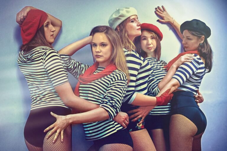 Five women in striped shirts and berets strike a pose, reminiscent of a French artistic style.
