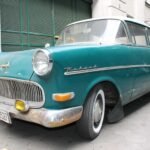 Teal 1950s Opel Rekord parked on a city street.
